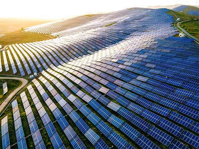 Solar panels lined up on hill with sunrise